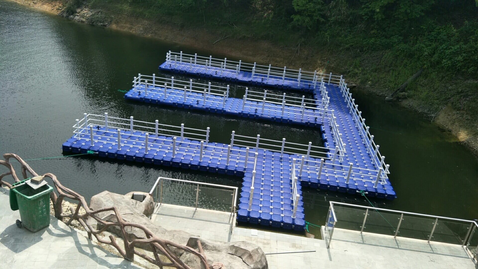 Blauwe modulaire drijvende steiger met witte leuningen, vingerpieren en een toegangsweg vanaf de wal