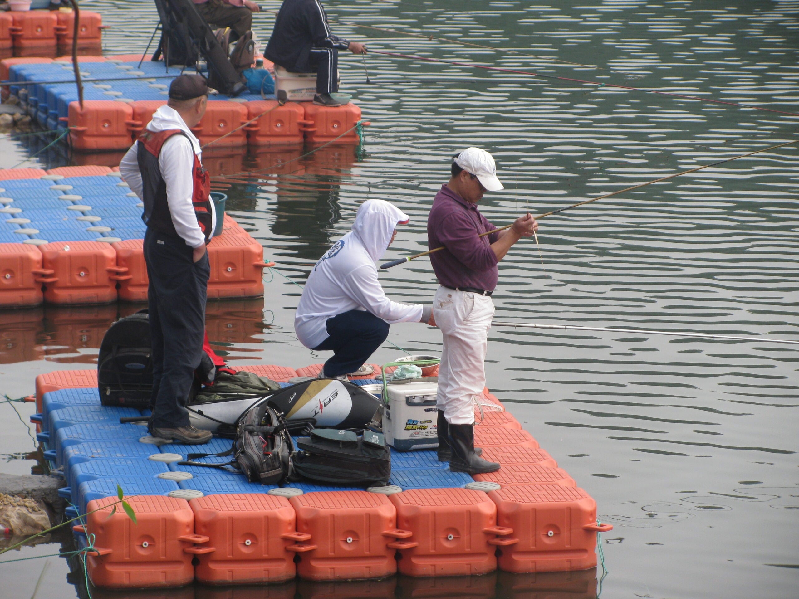 People with fishing equipment on a blue and orange modular platform